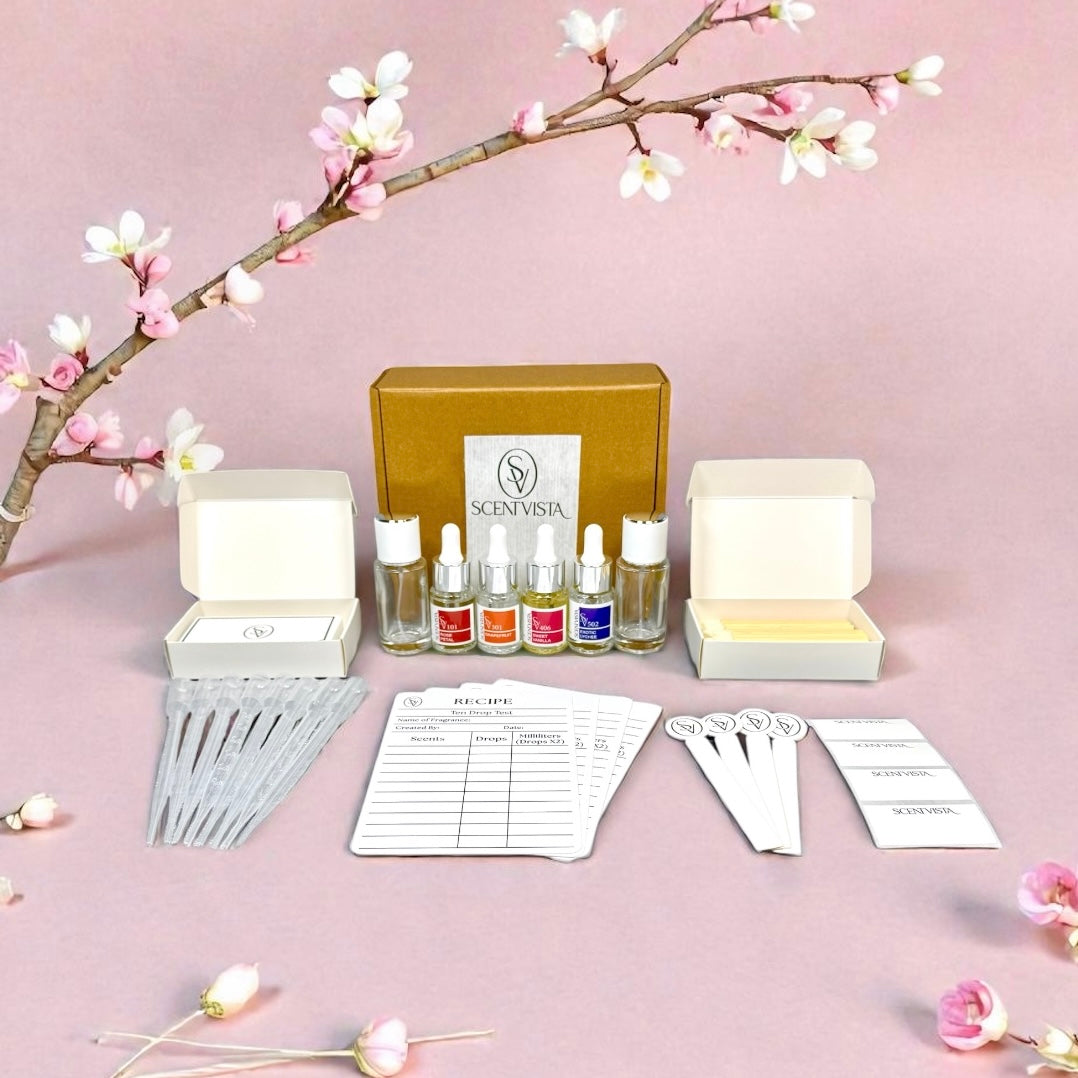 Fragrance kit with bottles, boxes, and a branch with flowers on a pink background