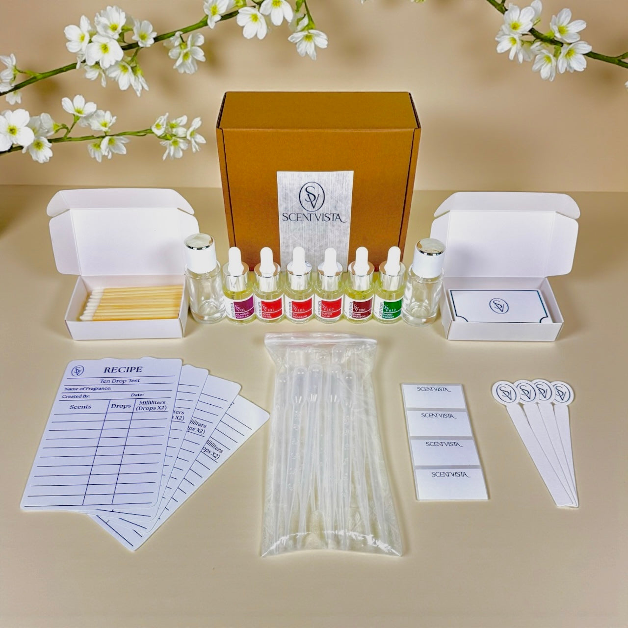 Scentvista fragrance designer kit with vials, boxes, and floral decorations on a beige background