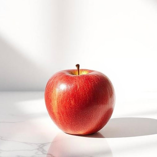 Red apple on a white surface with a white background representing the smell of Apple Orchard that is used to create custom perfumes and colognes.
