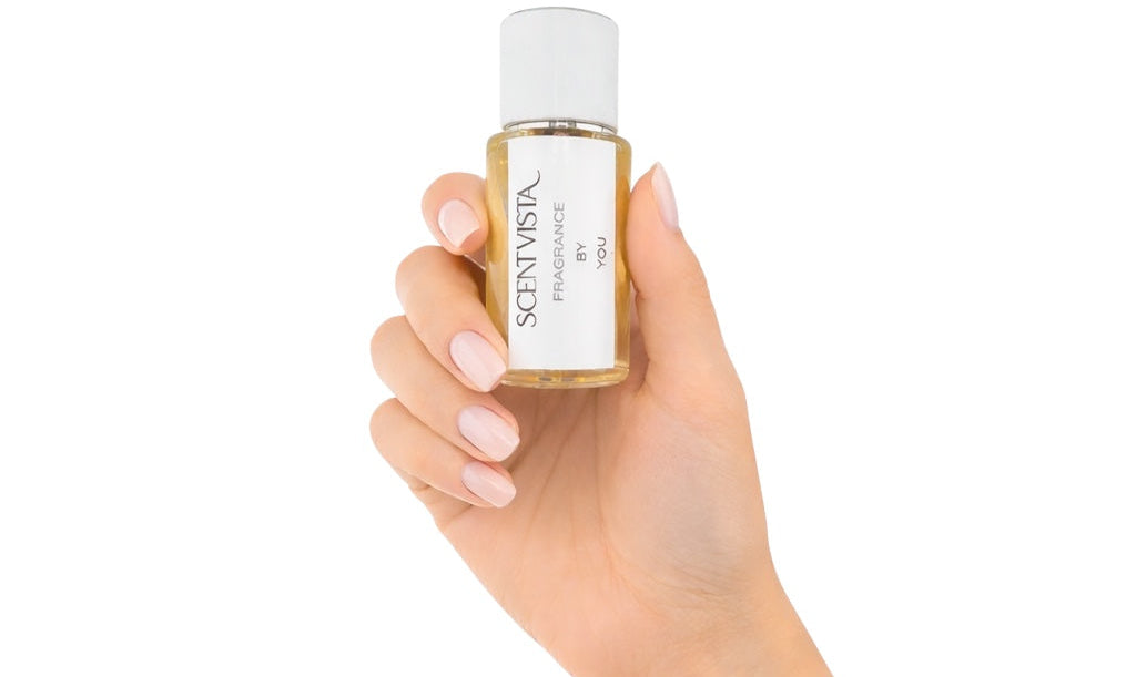 A hand holding a Scentvista fragrance spray bottle on a white background