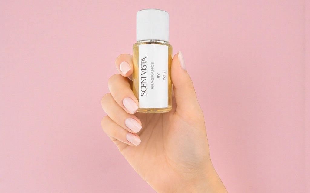 Hand holding a bottle of Scentista perfume against a pink background
